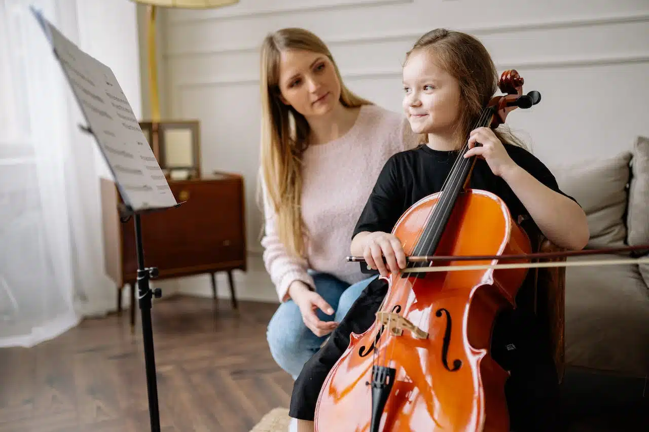 Child learning cello with her music teacher