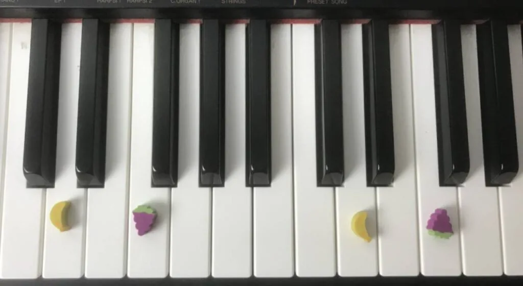 image of piano with fruit erasers on the keyboard.
